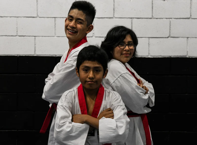 Tres jóvenes alumnos de Taekwondo en el dojang de Kyeongju, listos para entrenar.