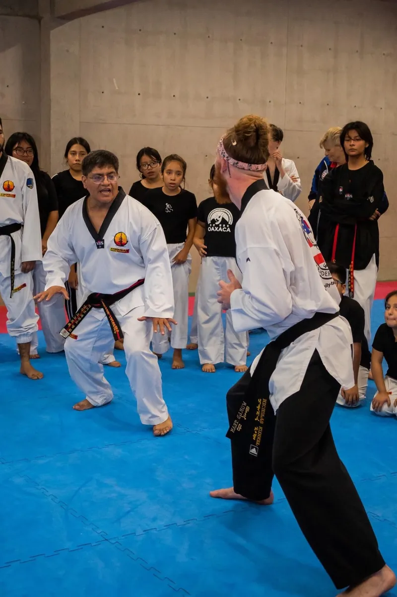 Maestro de Kyeongju explicando una técnica de defensa frente a un grupo de jóvenes y adultos durante un seminario.